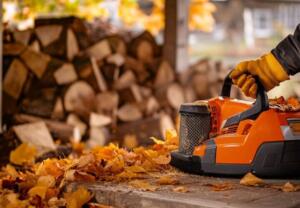 gloved hand holding chainsaw in autumn