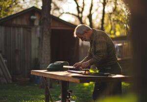 man sharpening mower blade outdoors