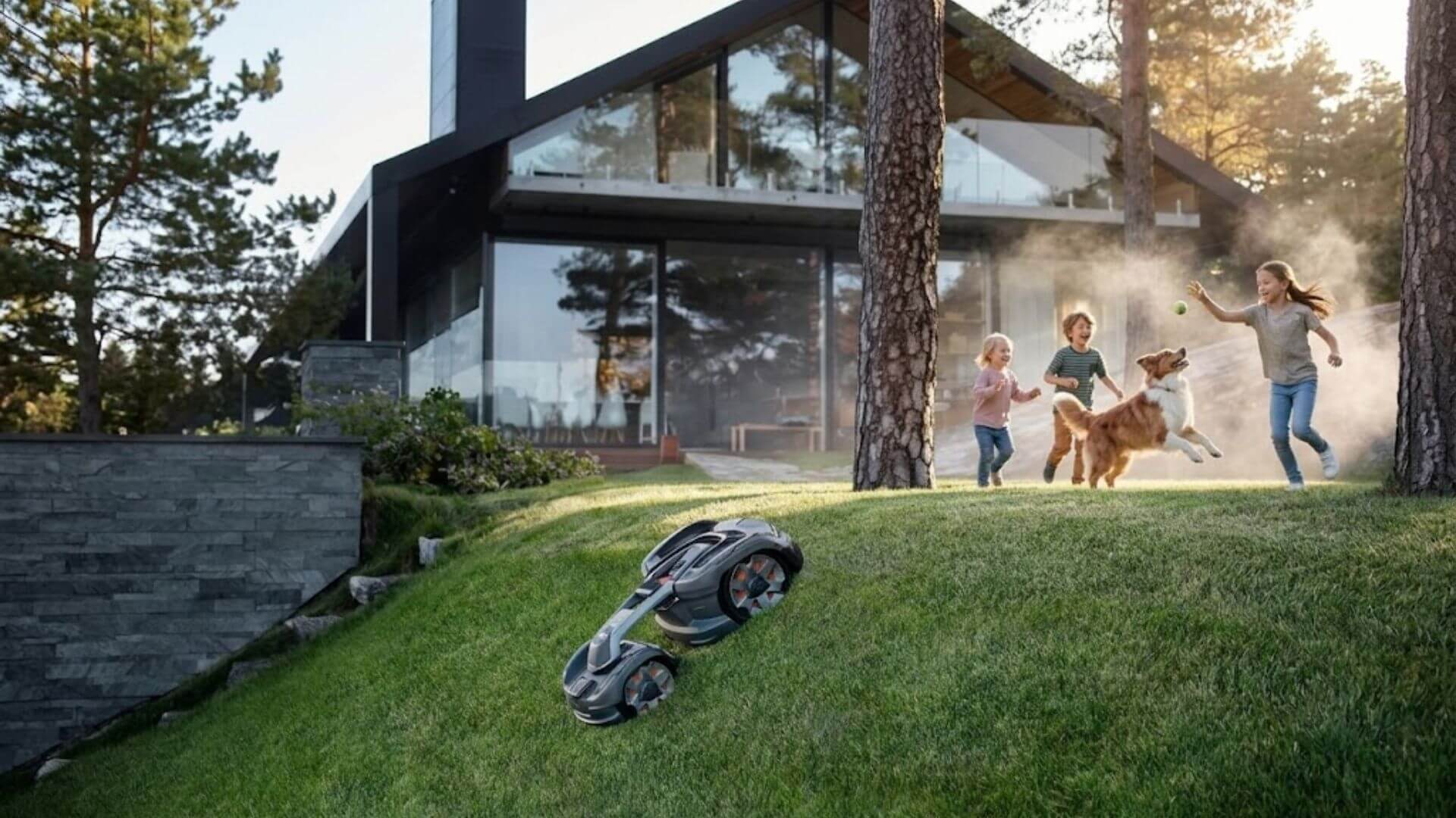Husqvarna AWD robotic mower operating on a steep residential slope while children play with a dog near a modern home.